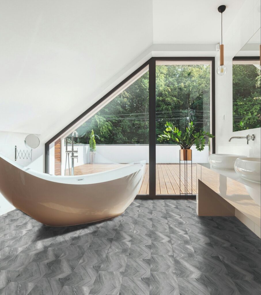 Modern bathroom featuring SmartDrop Tile-Grey Granite flooring, freestanding bathtub, large windows, double sinks, and views of a green outdoor area.