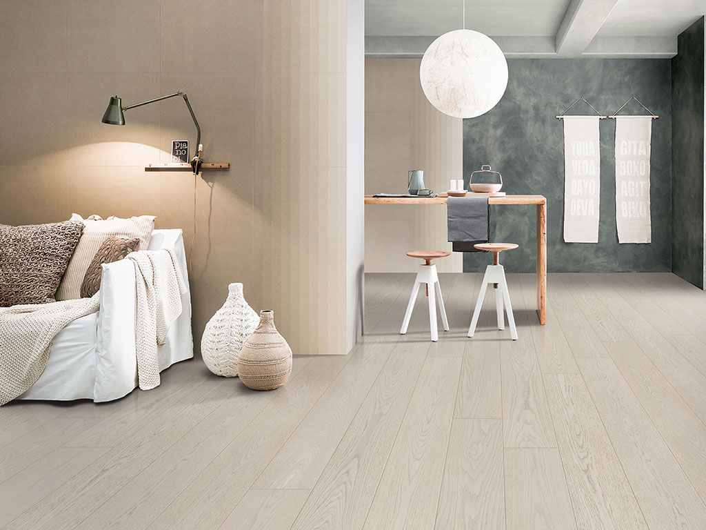 The Canvas-Spire-web complements a modern minimalist bedroom and dining area with light wood floors, neutral walls, a neat bed, and a small table with two stools under a round white pendant light.